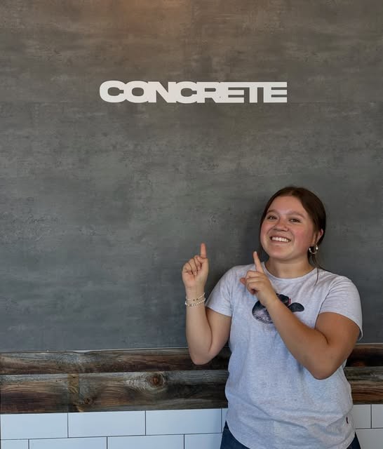 A Concrete Coffee barista beneath the Concrete sign on the shop wall